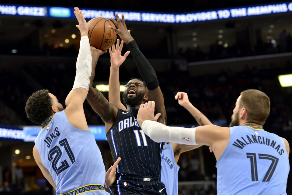 Orlando Magic forward James Ennis III (11) shoots between Memphis Grizzlies guard Tyus Jones (21) and center Jonas Valanciunas (17) during the second half of an NBA basketball game Tuesday, March 10, 2020, in Memphis, Tenn. (AP Photo/Brandon Dill)