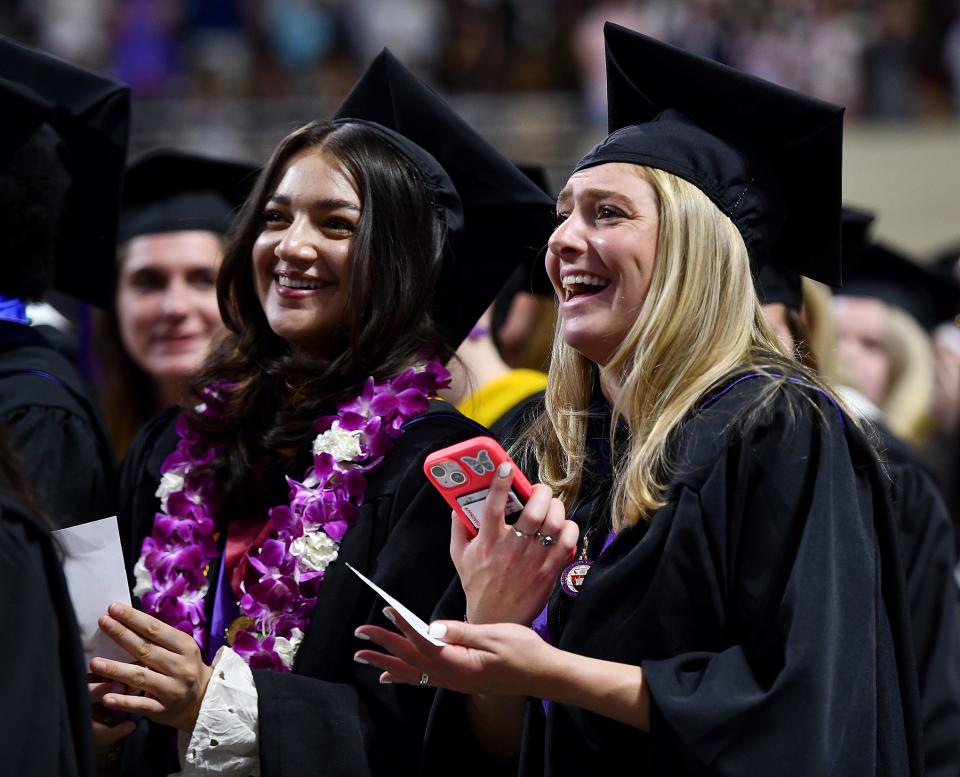 Jenna Giardina and Isabella Giaquinta laugh as families cheer during the College of the Holy Cross 177th graduation ceremony at the DCU Center Friday.