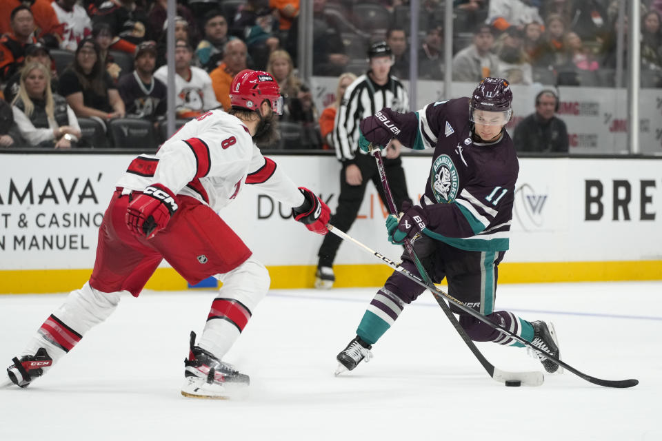 Anaheim Ducks' Trevor Zegras (11) shoots under defense by Carolina Hurricanes' Brent Burns (8) during the third period of an NHL hockey game Sunday, Oct. 15, 2023, in Anaheim, Calif. The Ducks won 6-3. (AP Photo/Jae C. Hong)