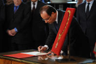 François Hollande reçoit l'insigne de Grand maître de l'Ordre de la Légion d'honneur avant de signer un registre avant de se rendre, entouré du président du Sénat et du président de l'Assemblée nationale, dans la salle des fêtes où l'attendent tous ses invités. AFP