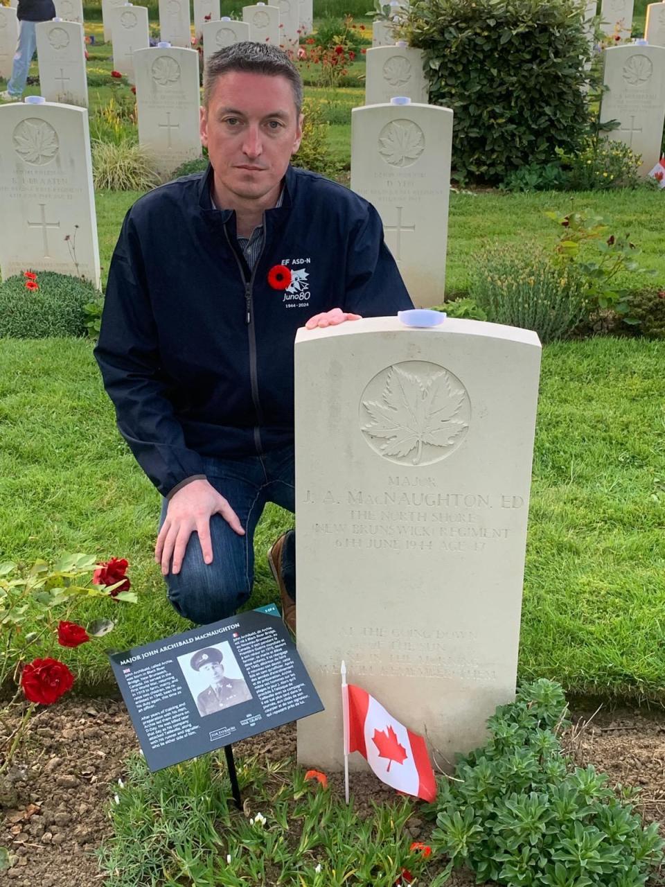 History teacher Brandon Savage kneels next to the grave of Major John Archibald MacNaughton of the North Shore (New Brunswick) Regiment. 