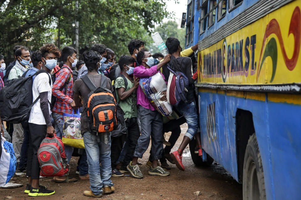 Commuters wearing face masks jostle for a ride on a bus discarding social distancing guidelines in Kolkata, India, Tuesday, July 21, 2020. With a surge in coronavirus cases in the past few weeks, state governments in India have been ordering focused lockdowns in high-risk areas to slow down the spread of infections. (AP Photo/Bikas Das)