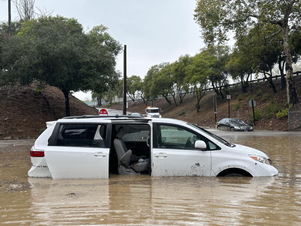 A vehicle is submerged in floodwaters near an overpass as rain comes down, Thursday, Dec. 21, 2023, in Santa Barbara, Calif. (AP Photo/Eugene Garcia)