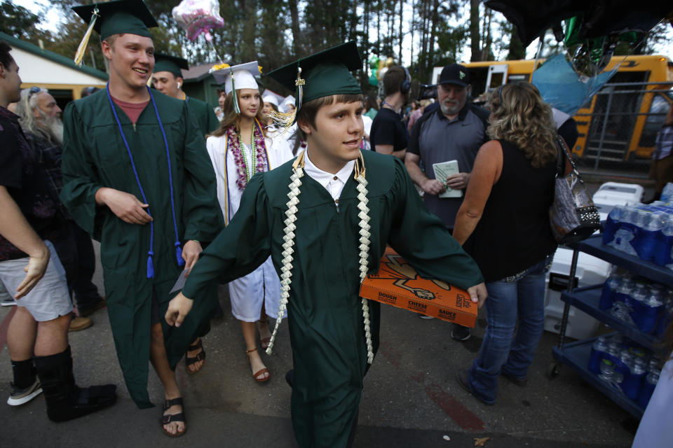 Ben Dees bring a pizza with him for the graduation ceremonies at Paradise High School in Paradise, Calif., Thursday June 6, 2019. Most of the students of Paradise High lost their homes when the Camp Fire swept through the area and the school was forced to hold classes in Chico. The seniors gathered one more time at Paradise High for graduation ceremonies. (AP Photo/Rich Pedroncelli)
