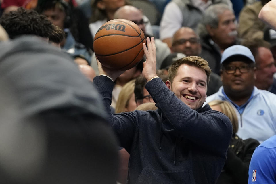 Dallas Mavericks guard Luka Doncic, with the night off for rest, gets ready to toss the game ball from the bench during the first first half of the team's NBA basketball game against the Houston Rockets in Dallas, Wednesday, Nov. 16, 2022. (AP Photo/LM Otero)