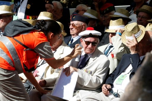 A Red Cross volunteer sprays water on a veteran during the ceremony at the Boulouris national cemetery in Saint-Raphael