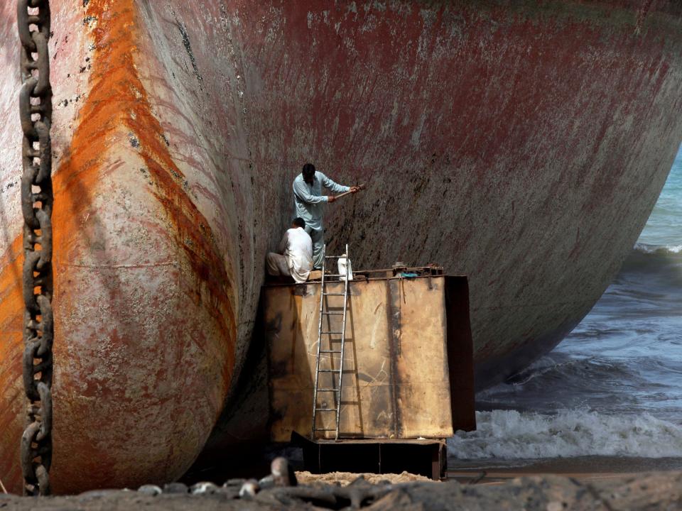 Labourers work without protective gear to separate parts of a ship for scrap metal at ship-breaking yard in Gadani, Baluchistan province