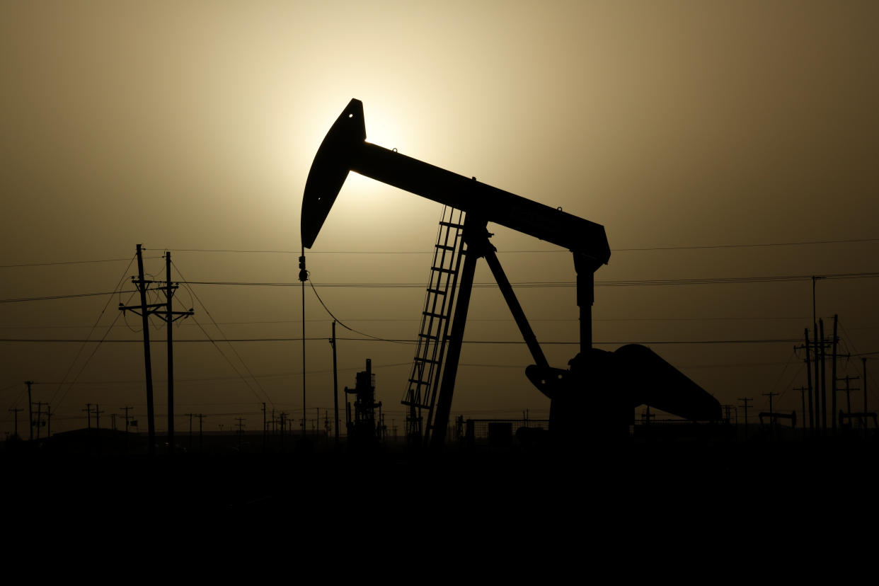 A pump jack operates at sunset in Midland, Texas