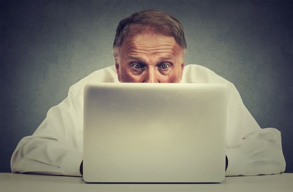 Older man looking at computer screen with a surprised look on his face.