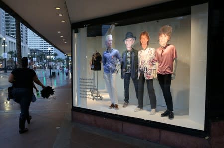 A woman walks past mannequins featuring the faces of The Rolling Stones in New Orleans