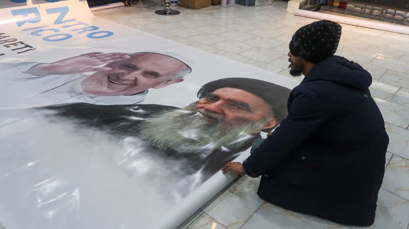 A worker rolls a poster of Pope Francis and Iraq's top Shi'ite cleric, Ayatollah Ali al-Sistani, ahead of the Pope's planned visit to Iraq, at a shop in Najaf