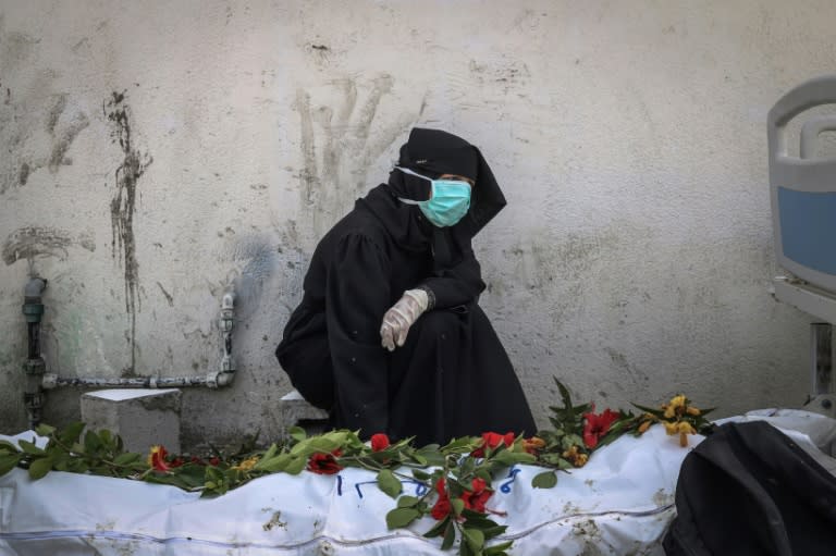 A woman mourns by a body unearthed at Nasser Hospital in Khan Yunis (-)