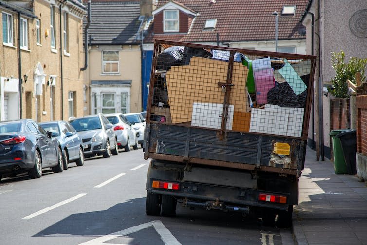 A private rubbish truck on the street, viewed from the back.