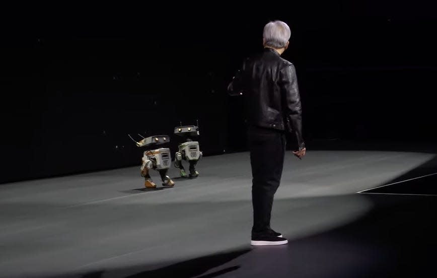 Jensen Huang looking at two robots onstage at Nvidia's GTC.
