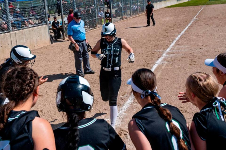 Kentwood players surround home plate to greet Sarah Wright after her home run in the bottom of the fifth inning of the District 2/3 tournament championship game against Skyview on Saturday, May 21, 2022, at Kent Service Fields in Kent, Wash.