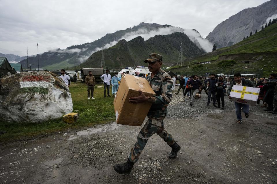 An Indian army soldier carries medicine and other items for victims of a cloudburst at Baltal, 105 kilometers (65miles) northeast of Srinagar, Indian controlled Kashmir, Saturday, July 9, 2022. At least eight pilgrims have been killed after a cloudburst triggered a flash flooding during an annual Hindu pilgrimage to an icy Himalayan cave in Indian-controlled Kashmir. Officials say the cloudburst near the hollowed mountain cave revered by Hindus on Friday sent a wall of water down a mountain gorge and swept about two dozen encampments and two makeshift kitchens. (AP Photo/Mukhtar Khan)