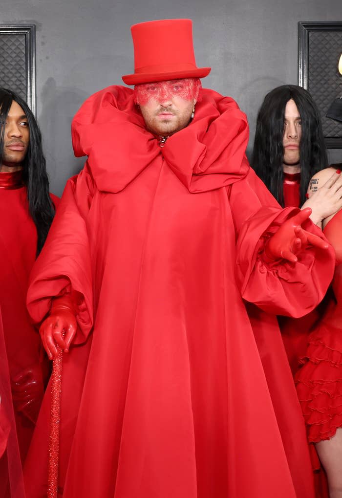 Sam in a long red gown with a cane, latex gloves, and top hat with lce