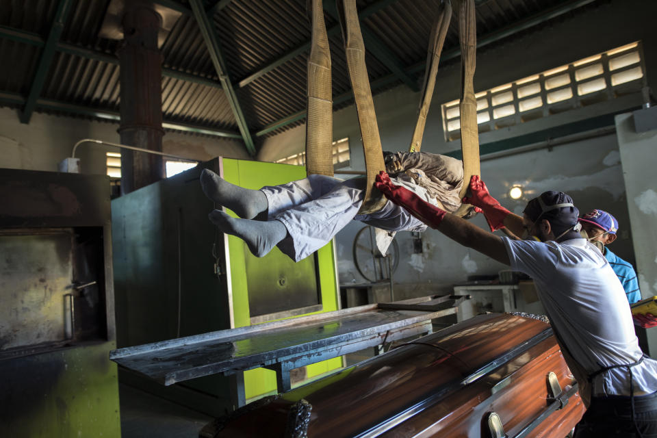 Cemetery workers lift a corpse from a coffin to a metal plate as they prepare the body for cremation at a cemetery in Maracaibo, Venezuela, Nov. 27, 2019. Some overcome the financial burden of a relative's death by renting caskets, a cheaper option than buying one. (AP Photo/Rodrigo Abd)