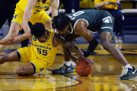 Michigan guard Eli Brooks (55) and Michigan State forward Aaron Henry (0) reach for the loose ball during the first half of an NCAA college basketball game, Thursday, March 4, 2021, in Ann Arbor, Mich. (AP Photo/Carlos Osorio)