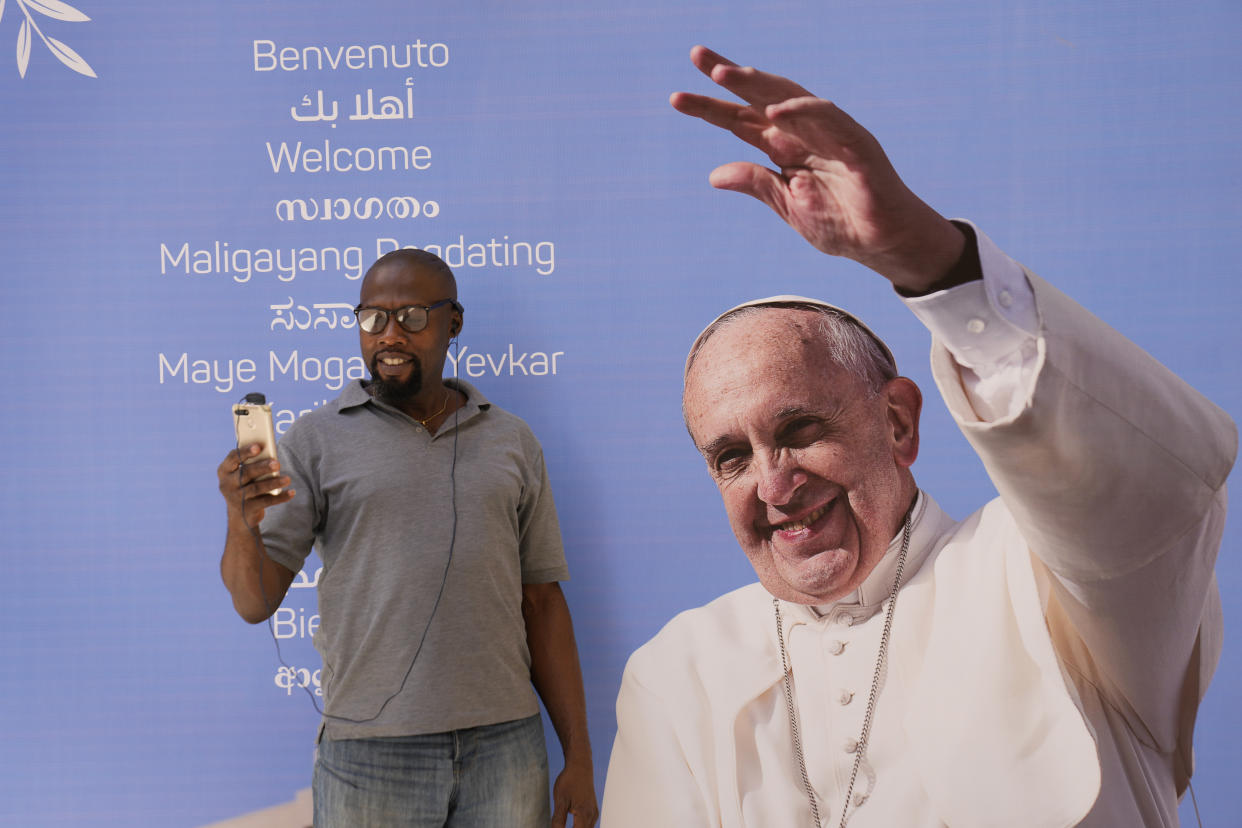 A man makes a video call through his mobile phone in front of Pope Francis portrait, outside the Sacred Heart church in Manama, Bahrain, Wednesday, Nov. 2, 2022. Pope Francis is making the Nov. 3-6 visit to participate in a government-sponsored conference on East-West dialogue and to minister to Bahrain's tiny Catholic community, part of his effort to pursue dialogue with the Muslim world. (AP Photo/Hussein Malla)