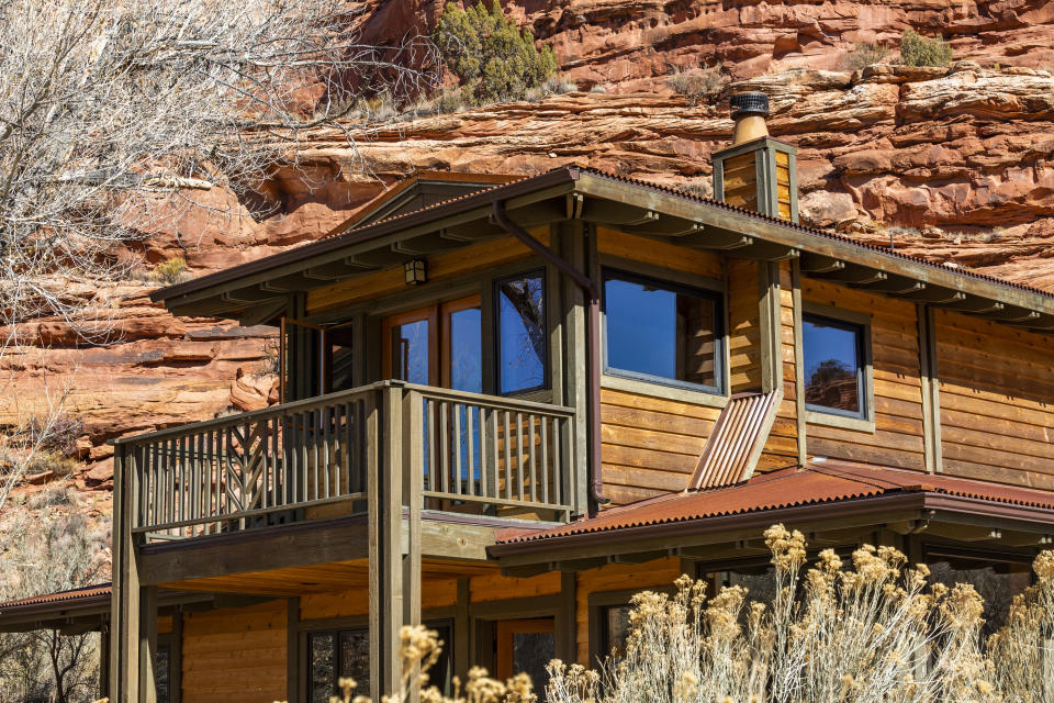 A wooden cabin with a balcony nestled against a rocky hillside