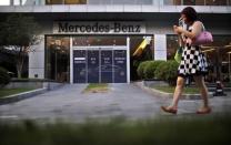 A woman walks past a Mercedes-Benz car dealership in downtown Shanghai in this August 5, 2014 file photo. REUTERS/Carlos Barria/Files