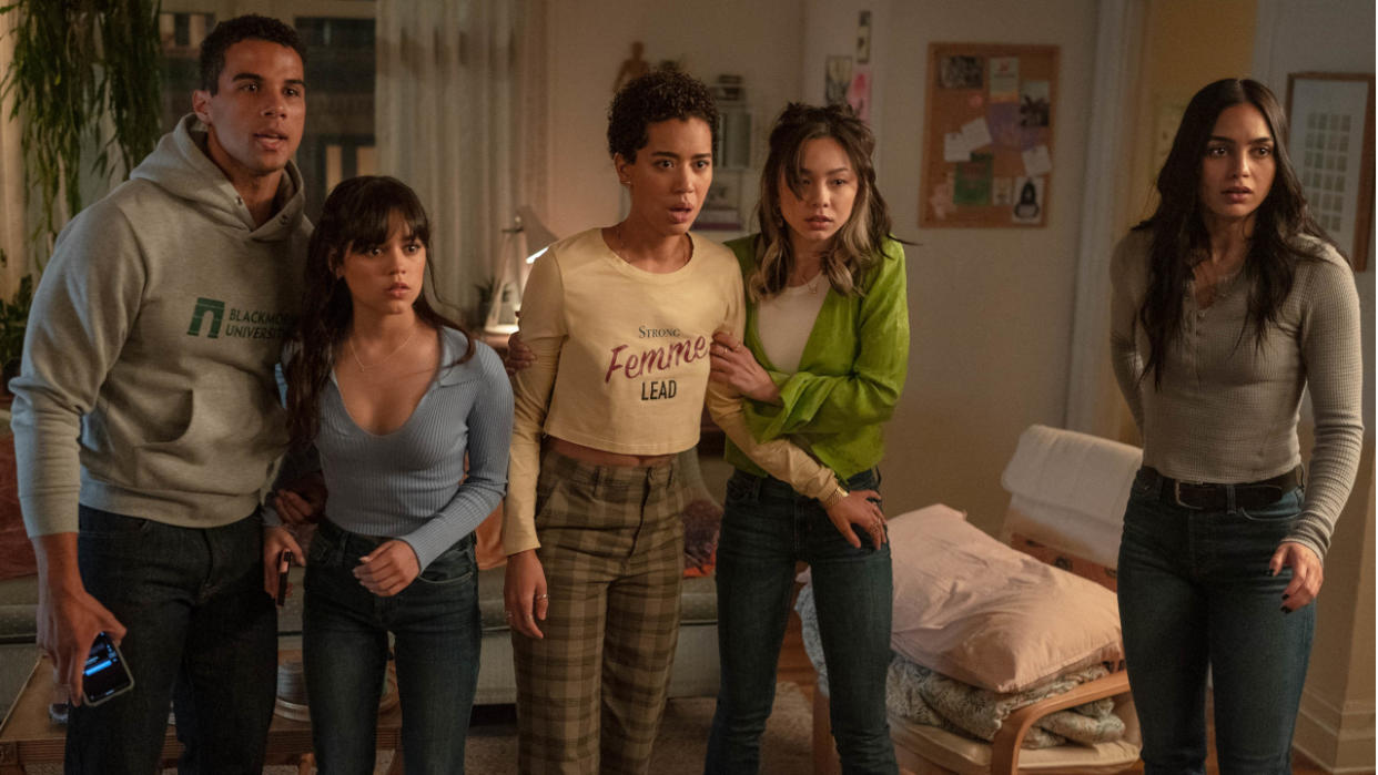  Mason Gooding, Jenna Ortega, Jasmin Savoy Brown, Devyn Nekoda, and Melissa Barrera stand shocked in the living room in Scream VI. 