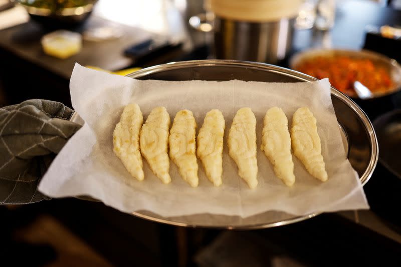 A chef holds up pieces of 3D-printed cultivated grouper fish before making them into a dish for a tasting at the offices of Steakholder Foods in Rehovot