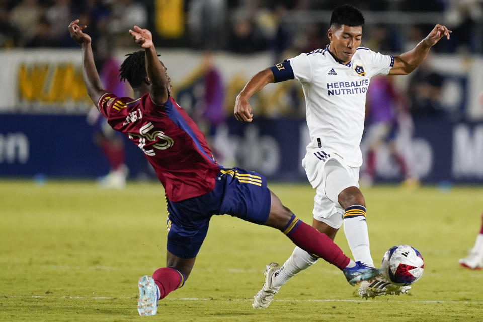 LA Galaxy midfielder Daniel Aguirre, right, dribbles the ball as Real Salt Lake midfielder Emeka Eneli slide-tackles during the second half of an MLS soccer match Saturday, Oct. 14, 2023, in Carson, Calif. (AP Photo/Ryan Sun)