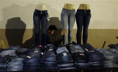 A Bolivian immigrant places a mannequin fitted with a pair of jeans on a table as he waits for customers along a street, in the Bras neighbourhood of Sao Paulo early morning August 9, 2013. Picture taken August 9, 2013. REUTERS/Nacho Doce