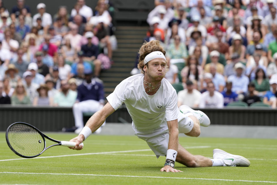 Russia's Andrey Rublev falls as he makes a return to Kazakhstan's Alexander Bublik in a men's singles match on day seven of the Wimbledon tennis championships in London, Sunday, July 9, 2023. (AP Photo/Kirsty Wigglesworth)