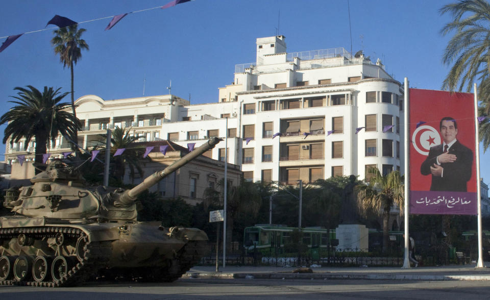 FILE - A tank is seen next to the portrait of former Tunisian President Zine El Abidine Ben Ali, on a street in Tunis, Saturday, Jan. 15, 2011. Despite an election debacle, Tunisia's increasingly authoritarian president appears determined to upend the country's political system, threatening to unravel the fragile democracy and collapse the economy in the North African nation that a decade ago stood out as a model of good governance and economic prosperity in the aftermath of the Arab Spring protests. (AP Photo/Thibault Camus, File)