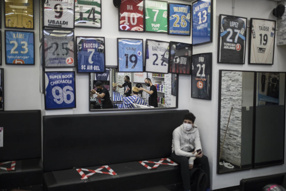 A customer waits for a haircut at the Lorenzo Styles barber shop in Marseille, southern France, Monday, May 11, 2020. France is beginning to reopen Monday after two months of virus confinement measures. Shops, hair salons and some other businesses are reopening Monday and French citizens no longer need a special permission form to leave the house. (AP Photo/Daniel Cole)