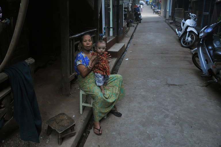 A woman holds a baby in a street in Mawlamyine, Myanmar's Mon state, on March 16, 2013. The rural Mon community of Ywarthit is a place for the old and the very young