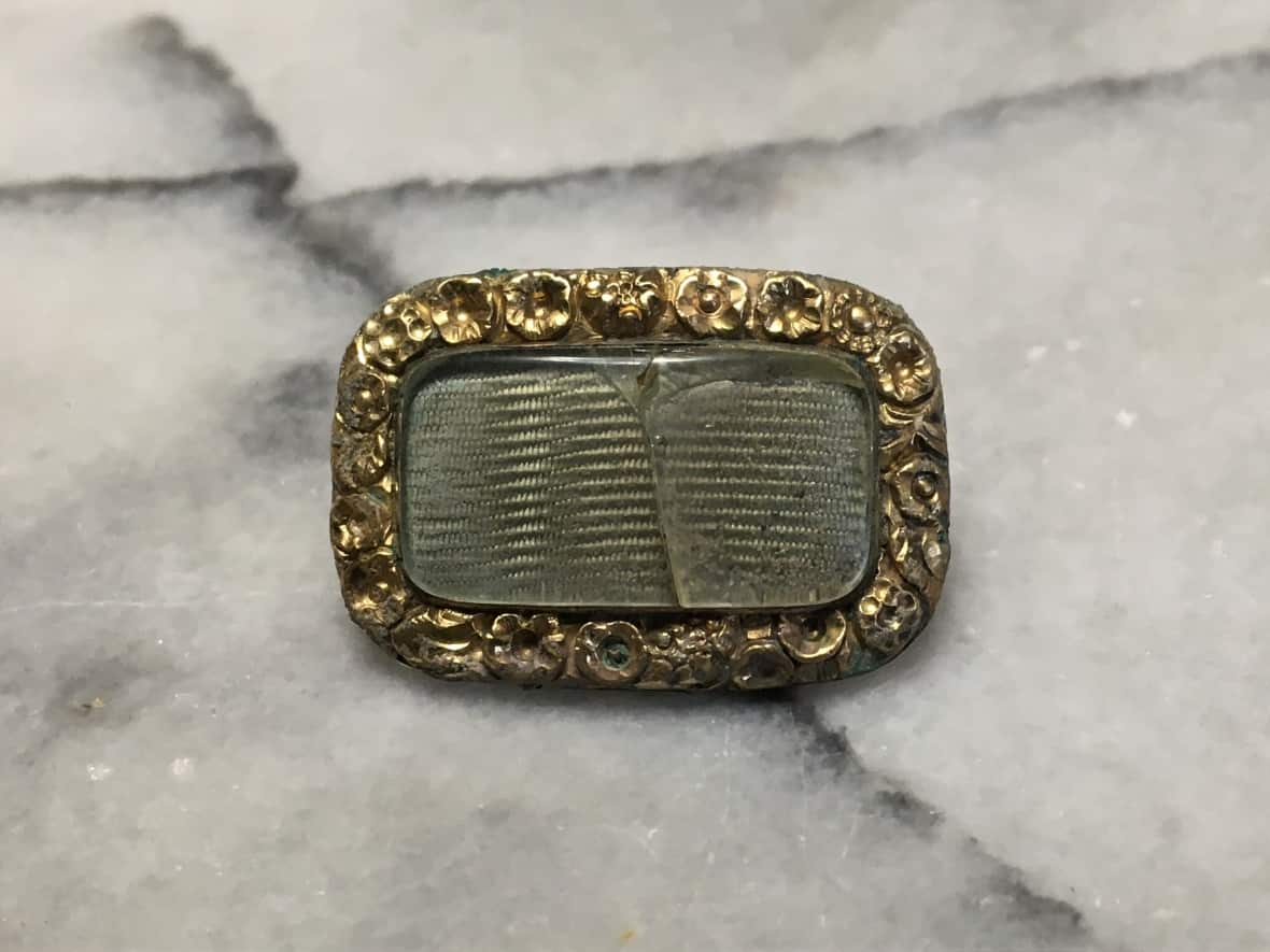 A mourning pin found by Travis Bussard on the banks of the North Thompson River in Kamloops, B.C. Bussard is hoping to find descendants of the man memorialized on the pin. (Travis Bussard - image credit)