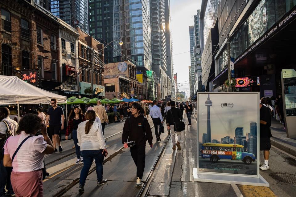 People walk by a movie poster outside the TIFF Bell Lightbox cultural centre, during Toronto International Film Festival, Thursday, Sept. 7, 2023, in Toronto. 