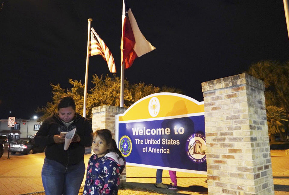 Asylum seeker Isabel, 21, left, texts her family members to let them know that she and her 7-year-old daughter, right, have been released after being processed at the Port of Entry in Brownsville, Texas, Tuesday, Dec. 17, 2019. The girl who is unable to contain her own waste due to a congenital illness and who had been refused entry to the United States three times has finally been allowed into the country. (AP Photo/Veronica G. Cardenas)