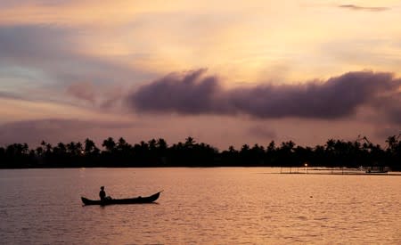 FILE PHOTO: A man rows his boat in the tributary waters of Vembanad Lake against the backdrop of pre-monsoon clouds on the outskirts of Kochi