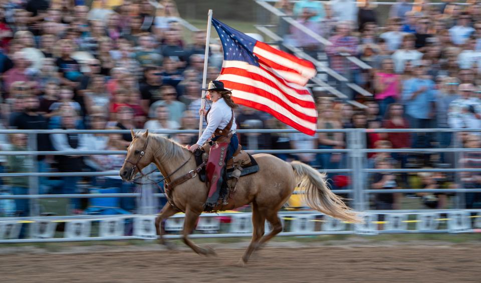 Miss UW-River Falls rodeo queen Jenna Stockinger carries the flag around the arena during the national anthem.