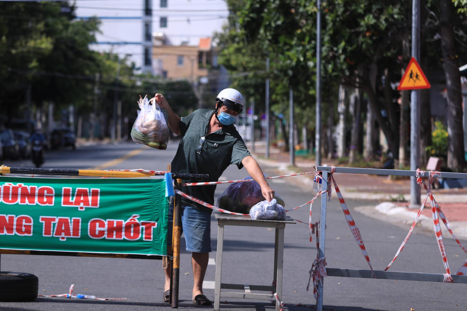 A man picks up food delivery at a checkpoint of a street cordoned off for the lockdown order in Vung Tau, Vietnam Monday, Sept. 6, 2021. Over 20 million Vietnamese students start a new school year on Monday, many of them on virtual classrooms as more than half of the country is in lockdown to contain a COVID-19 surge. (AP Photo/Hau Dinh)