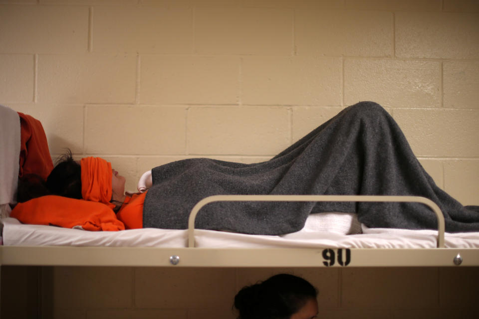 A woman lies on a bed in a dormitory at the Adelanto immigration detention center