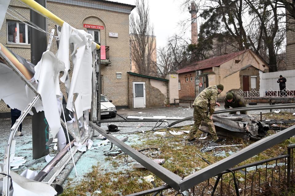 Police and security personnel inspect the remains of a shell in a street in Kyiv on February 24, 2022. - Russian President Vladimir Putin announced a military operation in Ukraine on Thursday with explosions heard soon after across the country and its foreign minister warning a 