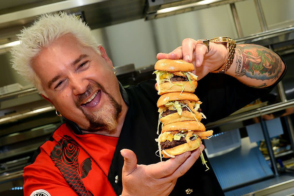 Chef and television personality Guy Fieri holds hamburgers in the kitchen during a welcome event for Guy Fieri's Vegas Kitchen & Bar at The Quad Resort & Casino on April 4, 2014 in Las Vegas