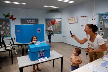 A mother takes a photograph of her daughter near a ballot box as Israelis vote in a parliamentary election at a polling station in Rosh Ha'ayin, Israel