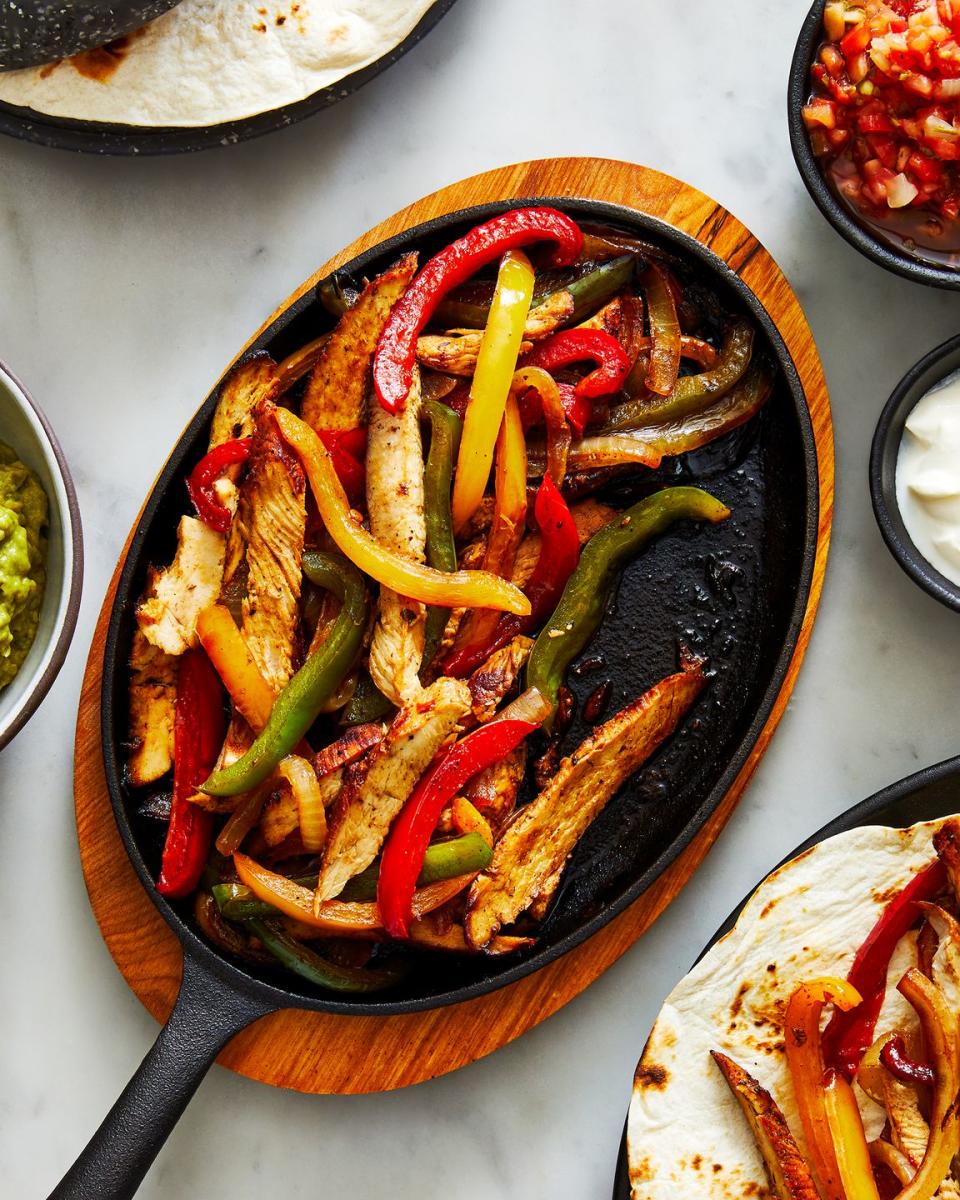 chicken fajitas on a steaming plate with peppers and onions