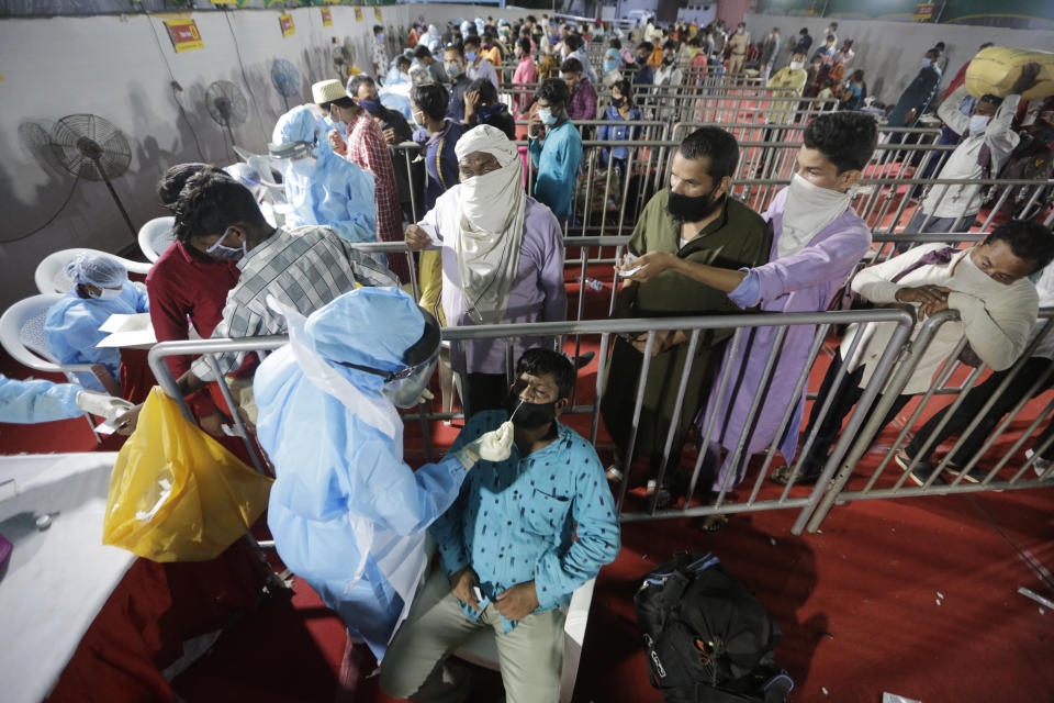 A health worker takes a nasal swab sample of a passenger to test for COVID-19 at a facility erected at a railway station to screen people coming from outside the city, in Ahmedabad, India, Friday, Sept. 18, 2020. India's coronavirus cases jumped by another 96,424 in the past 24 hours, showing little sign of leveling. India is expected to have the highest number of confirmed cases within weeks, surpassing the United States, where more than 6.67 million people have been infected. (AP Photo/Ajit Solanki)