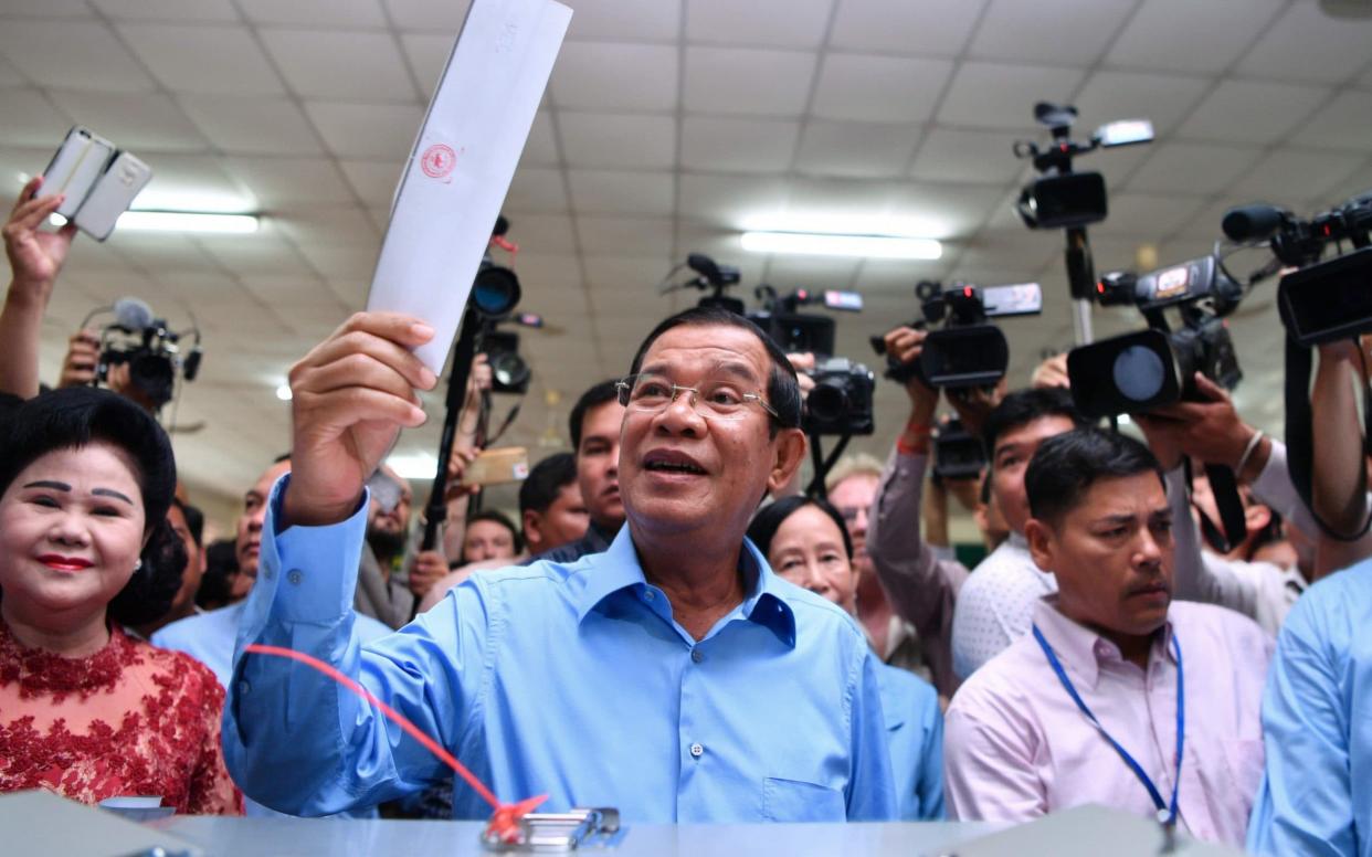 Hun Sen prepares to cast his vote during the general election as his wife Bun Rany, left, looks on in Phnom Penh - AFP