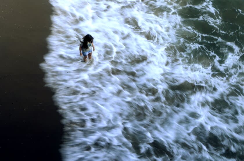 Santa Monica, CA - A beachgoer wades in the surf belowt the Santa Monica Pier on Monday, June 12, 2023. The ocean water around the pier is said to be among the most polluted in California, according to the latest report from Heal The Bay. Monday, June 12, 2023 in Santa Monica, CA. (Luis Sinco / Los Angeles Times)