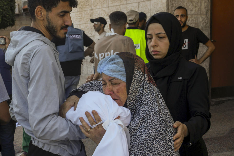 A Palestinian woman kisses the sheet-covered body of a child killed during an Israeli airstrike, Sunday, Oct. 15, 2023, outside al-Aqsa Hospital in Deir el-Balah, central Gaza Strip. (AP Photo/Adel Hana)