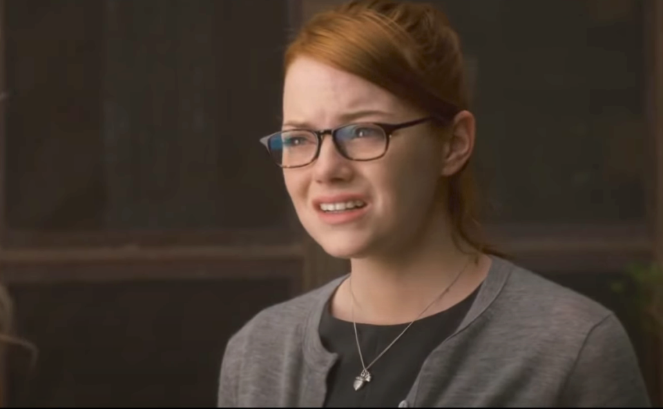 closeup of her wearing glasses and a frumpy cardigan